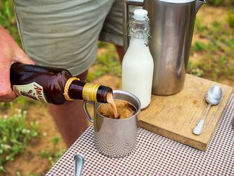 PHINDA GAME RESERVE, HLUHLUWE, KWAZULU-NATAL, SOUTH AFRICA - 2018/11/14: A guide pours Amarula into a coffee at the Phinda Private Game Reserve, an andBeyond owned nature reserve in eastern South Africa. Hotel and safari owner and operator, andBeyond uses funds derived from their luxury tourism operations to fund conservation and development projects in South Africa. Amarula is made from the indigenous marula tree, known locally as Elephant Tree or Marriage Tree. (Photo by Leisa Tyler/LightRocket via Getty Images)