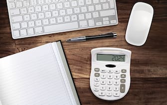 High angle view of calculator, keyboard and mouse with pen and pad on desk