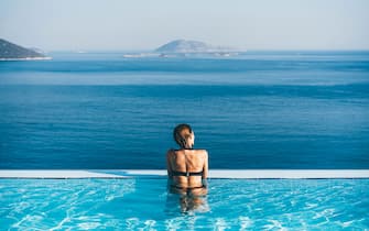 Woman in infinity pool admiring scenic view.