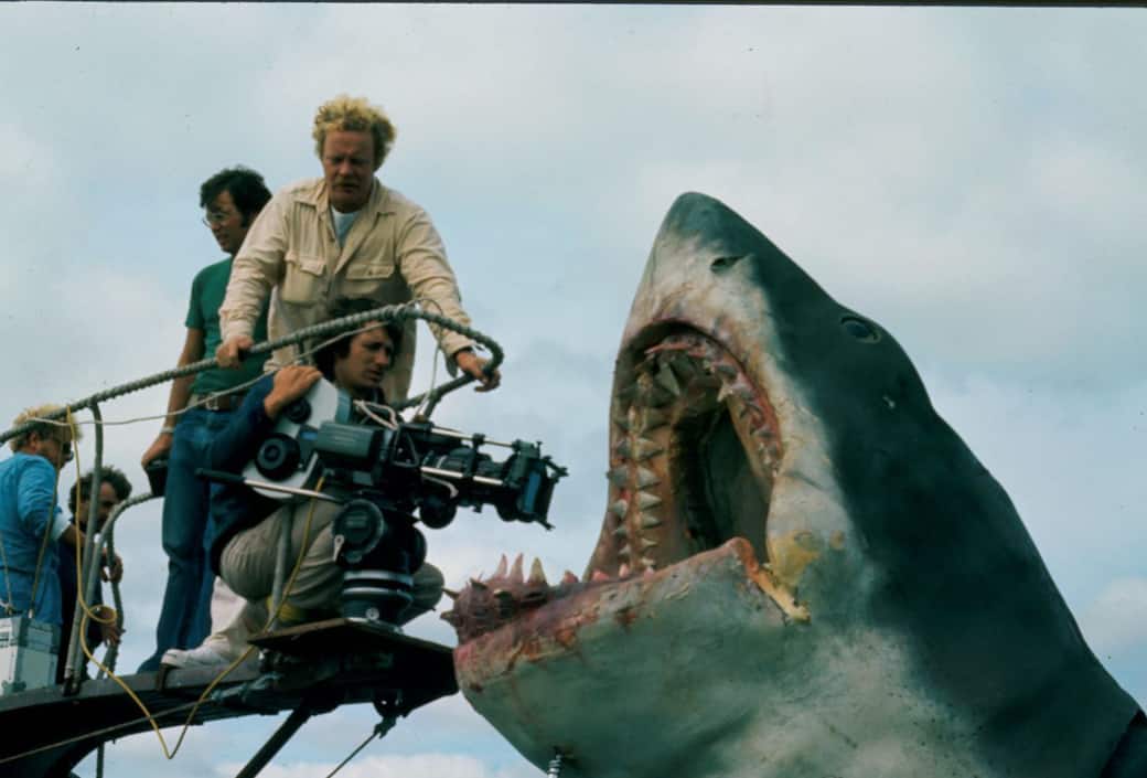 Director Steven Spielberg, kneeling with camera, during production of Jaws (1975). Others unidentified. Courtesy of Margaret Herrick Library, Academy of Motion Picture Arts and Sciences