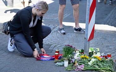 A woman kneels at a makeshift memorial of flowers and candles for the victims on August 24, 2024 close to the scene where at least three people were killed and several injured when a man attacked them with a knife on late August 23, 2024 in Solingen, western Germany, during a festival to mark the city's 650th anniversary. German police stepped up a major hunt for a man who stabbed three people to death and wounded eight others at the street festival, authorities said. Police closed off the centre of Solingen after the attack at the city's "Festival of Diversity". A police statement said five of the wounded were in "serious" condition. (Photo by Roberto Pfeil / AFP)