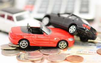 Car insurance concept with colorful toy cars, car key, coins and bills
