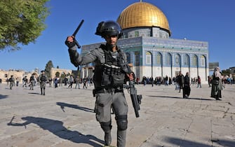 TOPSHOT - A member of the Israeli security forces lifts his batton in front of the Dome of the Rock mosque during clashes at Jerusalem's Al-Aqsa mosque compound, on April 15, 2022. - Witnesses said that Palestinian protestors threw stones at Israeli security forces, who fired rubber bullets at some of the demonstrators. (Photo by AHMAD GHARABLI / AFP) (Photo by AHMAD GHARABLI/AFP via Getty Images)