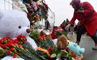 A woman lays flowers at a makeshift memorial in front of the Crocus City Hall, a day after a gun attack in Krasnogorsk, outside Moscow, on March 23, 2024. Camouflaged assailants opened fire at the packed Crocus City Hall in Moscow's northern suburb of Krasnogorsk on March 22, 2024, evening ahead of a concert by Soviet-era rock band Piknik in the deadliest attack in Russia for at least a decade. Russia on March 23, 2024, said it had arrested 11 people -- including four gunmen -- over the attack on a Moscow concert hall claimed by Islamic State, as the death toll rose to over 100 people. (Photo by Olga MALTSEVA / AFP) (Photo by OLGA MALTSEVA/AFP via Getty Images)