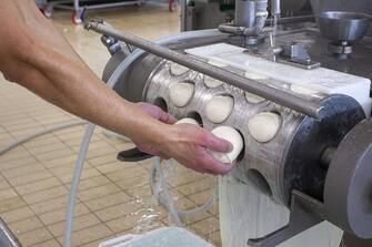BARI, ITALY - DECEMBER 12: The cheesemakers of the La Gioia Bella dairy produce and package the typical "mozzarella" of Gioia del Colle on December 12, 2020 in Bari, Italy. Mozzarella di Gioia del Colle has officially obtained the Dop mark at European level. The implementing regulation that registers the product in the EU register of quality foods was in fact published in the Official Journal of the European Union. After a long process at national level, the application was submitted in October 2019, but the practice had slowed down mainly due to the objection of Germany and the Organization of American Cheese Exporters (Usdec) on the term "Mozzarella" , because it was to be considered generic and therefore could not be subject to protection. (Photo by Donato Fasano/Getty Images)