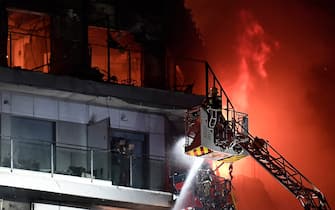 TOPSHOT - Two residents stand on a balcony, prior to being rescued, as firefighters battle a huge fire raging through a multistorey residential block in Valencia on February 22, 2024. (Photo by Jose Jordan / AFP) (Photo by JOSE JORDAN/AFP via Getty Images)