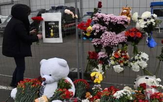 A woman lays flowers at a makeshift memorial in front of the Crocus City Hall, a day after a gun attack in Krasnogorsk, outside Moscow, on March 23, 2024. Camouflaged assailants opened fire at the packed Crocus City Hall in Moscow's northern suburb of Krasnogorsk on March 22, 2024, evening ahead of a concert by Soviet-era rock band Piknik in the deadliest attack in Russia for at least a decade. Russia on March 23, 2024, said it had arrested 11 people -- including four gunmen -- over the attack on a Moscow concert hall claimed by Islamic State, as the death toll rose to over 100 people. (Photo by Olga MALTSEVA / AFP) (Photo by OLGA MALTSEVA/AFP via Getty Images)