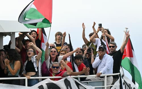 People aboard a boat wave Palestinian flags as they arrive to take part in a demonstration in support of Gaza and Palestinian people at Venice Lido during the 82nd Venice International Film Festival, on August 30, 2025. (Photo by Stefano RELLANDINI / AFP)