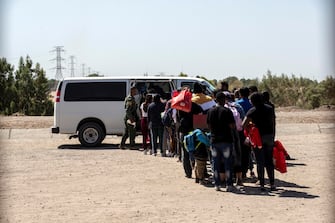 epa10620083 Migrants wait to be brought by a Border Patrol officer to a processing center along the border of Mexico and the United States, in Yuma, Arizona, USA, 10 May 2023. A significant increase in the number of migrant crossings is expected as the COVID-era Title 42 policy, which allowed for a quick expulsion of illegal immigrants, is set to expire on 11 May.  EPA/ETIENNE LAURENT