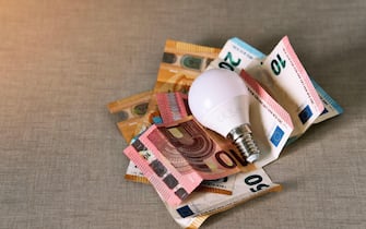 Several euro bills with a light bulb representing the rise in the price of electricity