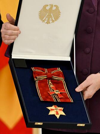 epa10577209 Former German Chancellor Angela Merkel poses with the box after she was awarded the 'Grand Cross of the Order of Merit of the Federal Republic of Germany' by German President Frank-Walter Steinmeier during a ceremony in Berlin, Germany, 17 April 2023.  EPA/FILIP SINGER