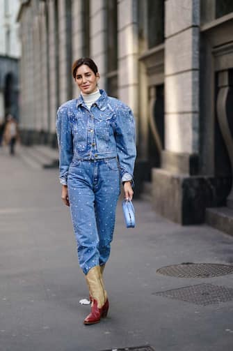 MILAN, ITALY - FEBRUARY 22: Gala Gonzalez wears a blue denim jacket with shoulder pads, a white turtleneck pullover, blue denim pants, cowboy boots, a bag, outside Philosophy, during Milan Fashion Week Fall/Winter 2020-2021 on February 22, 2020 in Milan, Italy. (Photo by Edward Berthelot/Getty Images)