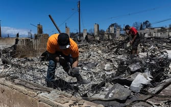 epa10795986 Lester (L) searches for the urn with the ashes of his son in the ruins of what once was his bedroom next to Lotario (R) the owner of the house destroyed by a wild fire in Lahaina, Hawaii, USA, 11 August 2023. At least 67 people were killed in the wildfires buring in Maui, which is considered the largest natural disaster in Hawaii's state history.  EPA/ETIENNE LAURENT