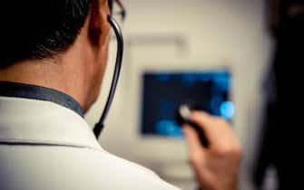 Persona con il camice davanti ad un apparecchio medico