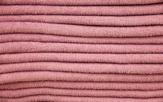 Stack of terry towels, selective focus. Soft background, pink bath textile close up