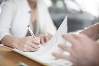 Cape Town, South Africa,female signing paperwork at desk, car dealership