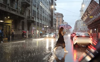 donna attraversa la strada sotto la pioggia