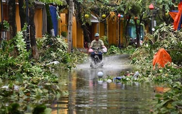 TOPSHOT - A man rides a motorbike in a flooded street following the passage of typhoon Noru in Hoi An city, Quang Nam province on September 28, 2022. (Photo by Nhac NGUYEN / AFP) (Photo by NHAC NGUYEN/AFP via Getty Images)
