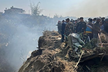 Rescuers and onlookers gather at the site of a plane crash in Pokhara on January 15, 2023. - An aircraft with 72 people on board crashed in Nepal on January 15, Yeti Airlines and a local official said. (Photo by Krishna Mani BARAL / AFP) (Photo by KRISHNA MANI BARAL/AFP via Getty Images)