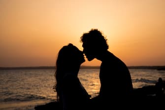 Detail of heterosexual young couple ready to kiss each other passionately with beach sunset background. Formentera, Balearic Islands, Spain, Europe.