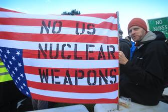 LAKENHEATH, ENGLAND - NOVEMBER 19: A protester holds an upside down United States flag written with the slogan 'No US Nuclear Weapons' on November 19, 2022 in Lakenheath, England. The protest was organised by the Campaign for Nuclear Disarmament (CND), whose supporters oppose the potential return of nuclear weapons to military bases in the UK, such as RAF Lakenheath. (Photo by Martin Pope/Getty Images)