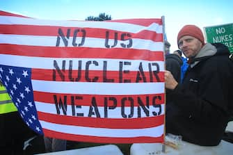 LAKENHEATH, ENGLAND - NOVEMBER 19: A protester holds an upside down United States flag written with the slogan 'No US Nuclear Weapons' on November 19, 2022 in Lakenheath, England. The protest was organised by the Campaign for Nuclear Disarmament (CND), whose supporters oppose the potential return of nuclear weapons to military bases in the UK, such as RAF Lakenheath. (Photo by Martin Pope/Getty Images)