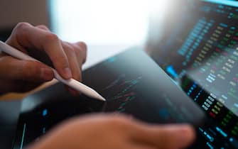 A business person tracking the technical movement of a stock chart on a computer screen.