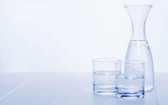 Water Carafe and Two Glasses - a carafe of water on a table with two glasses, blue toned, horizontal.