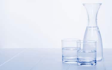 Water Carafe and Two Glasses - a carafe of water on a table with two glasses, blue toned, horizontal.