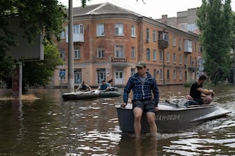 Volunteers carry local residents on boats during an evacuation from a flooded area in Kherson on June 8, 2023, following damages sustained at Kakhovka hydroelectric power plant dam. Ukrainian President Volodymyr Zelensky visited the region flooded by the breached Kakhovka dam on June 8, 2023, as the regional governor said 600 square kilometres were underwater. (Photo by ALEKSEY FILIPPOV / AFP)