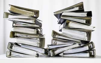 stacks of many ring binder with files, folders and documents on an office desk, concept for too much work and burn out in the business, selected focus