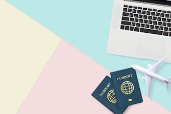 flat lay of passport , white plane model and computer laptop on pastel blue ,yellow and pink color background with copy space. travel , visa and vacat
