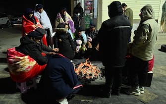Residents keep warm around fires after an earthquake in Jishishan County, in northwest China’s Gansu province on December 19, 2023. At least 116 people were killed when an earthquake collapsed buildings in northwest China, state media reported on December 19, as rescue workers raced to start digging through rubble in freezing conditions. (Photo by CNS / AFP) / China OUT