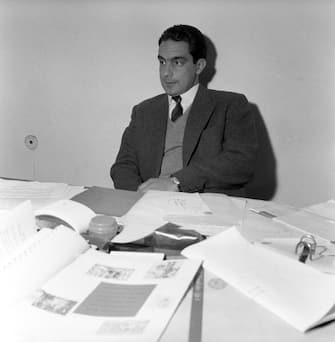Italo Calvino, italian writer and Einaudi publishing company's associate, sits at his desk filled with paperwork. Turin (Italy), July 1959. (Photo by Emilio Ronchini/Mondadori via Getty Images)