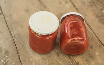Typical canned tomatoesin glass hars on wooden table.