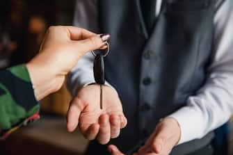 A close up of an unrecognisable woman handing her car keys over to the hotel concierge.