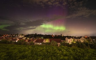 Image of strong Aurora over a busy residential area showing strong red and green pillars. Image shot in Perthshire, Scotland.