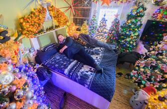 30 November 2023, Lower Saxony, Rinteln: Susanne and Thomas Jeromin lie on their bed surrounded by Christmas trees in their home in the Schaumburg district. 555 Christmas trees and almost 108,000 Christmas baubles: During Advent, the Jeromin family's house shines as a colorful Christmas world. Photo: Julian Stratenschulte/dpa (Photo by Julian Stratenschulte/picture alliance via Getty Images)