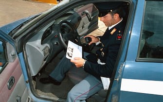 Un poliziotto guarda una foto segnaletica di Attilio Cubeddu