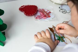 The hand of the child make snowman with needle and thread for christmas greeting card. Hobby concept. Handmade.