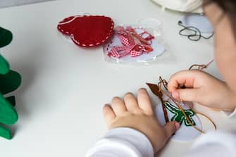 The hand of the child make snowman with needle and thread for christmas greeting card. Hobby concept. Handmade.