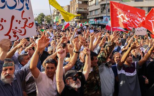 Iranians lift flags and placards during a rally protesting the US attack on Iran in Enghelab Square in Tehran on June 22, 2025. Iran's President Masoud Pezeshkian condemned US strikes on nuclear sites on June 22, saying in his first response that the attack revealed Washington was "behind" Israel's military campaign in the Islamic republic. (Photo by ATTA KENARE / AFP)