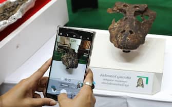 epa10925047 A woman takes a picture of the fossil of a new ancient alligator species, 'Alligator Munensis', during a press conference at the Mineral Resources Department in Bangkok, Thailand, 18 October 2023. The new species Alligator Munensis' fossil was discovered in April 2005 in Nakhon Ratchasima province of Thailand and is at most 230,000 years old.  EPA/NARONG SANGNAK