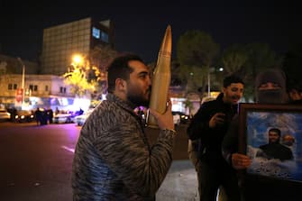 A demonstrator kisses a bullet shell replica as others gather at Palestine Square in Tehran on April 14, 2024, after Iran launched a drone and missile attack on Israel. Iran's Revolutionary Guards confirmed early April 14, 2024 that a drone and missile attack was under way against Israel in retaliation for a deadly April 1 drone strike on its Damascus consulate. (Photo by ATTA KENARE / AFP) (Photo by ATTA KENARE/AFP via Getty Images)