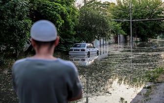 epa10676371 A man looks on as a car is parked in a flooded street of Kherson, Ukraine, 06 June 2023.Ukraine has accused Russian forces of destroying a critical dam and hydroelectric power plant on the Dnipro River in the Kherson region along the front line in southern Ukraine on 06 June. A number of settlements were completely or partially flooded, Kherson region governor Oleksandr Prokudin said on telegram. Russian troops entered Ukraine on 24 February 2022 starting a conflict that has provoked destruction and a humanitarian crisis.  EPA/IVAN ANTYPENKO