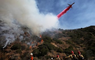Los Angeles LOS ANGELES, CALIFORNIA - OCTOBER 21: A firefighting aircraft drops the fire retardant Phos-Chek as firefighters (BOTTOM) watch during a wildfire threatening nearby hillside homes in the Pacific Palisades neighborhood on October 21, 2019 in Los Angeles, California. The fire scorched at least 40 acres and prompted mandatory evacuations. (Photo by Mario Tama/Getty Images)