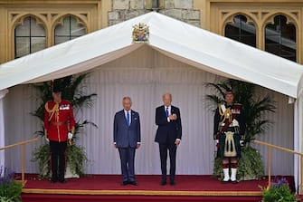 US President Joe Biden and Britain's King Charles III on the dais, listen to the US National Anthem played by the Band of the Welsh Guards, during a ceremonial welcome in the Quadrangle at Windsor Castle in Windsor on July 10, 2023. US President Joe Biden was in Britain on Monday, where he met with Prime Minister Rishi Sunak and King Charles III, before going on to a NATO summit in Lithuania. (Photo by Ben Stansall / POOL / AFP) (Photo by BEN STANSALL/POOL/AFP via Getty Images)
