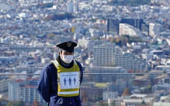 epa08889218 A security guard wearing a face mask stands on an observation deck in Tokyo, Japan, 04 December 2020 (issued 17 December 2020). According to media reports, Tokyo recorded more than 800 infection of SARS-CoV-2 on 17 December, a record daily number.  EPA/FRANCK ROBICHON