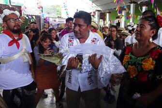 Victor Hugo Sosa, Mayor of San Pedro Huamelula, holds a spectacled caiman (Caiman crocodilus) called "La NiÃ±a Princesa" ("The Princess Girl") before marrying her in San Pedro Huamelula, Oaxaca state, Mexico on June 30, 2023. This ancient ritual of more than 230 years unites two ethnic groups in marriage to bring prosperity and peace. The spectacled caiman (Caiman crocodilus) is paraded around the community before being dressed as a bride and marrying the Mayor. According to beliefs, this union between the human and the divine will bring blessings such as a good harvest and abundant fishing. (Photo by RUSVEL RASGADO / AFP) (Photo by RUSVEL RASGADO/AFP via Getty Images)