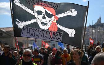 Demonstrators hold a banner depicting a pirate skull as they take part in the 11th nation day of action, after the government pushed a pensions reform through parliament without a vote, using the article 49.3 of the constitution, in Marseille, southeastern France, on April 6, 2023. - France on April 6, 2023 braced for another day of protests and strikes to denounce French President's pension reform one day after talks between the government and unions ended in deadlock. (Photo by CHRISTOPHE SIMON / AFP)